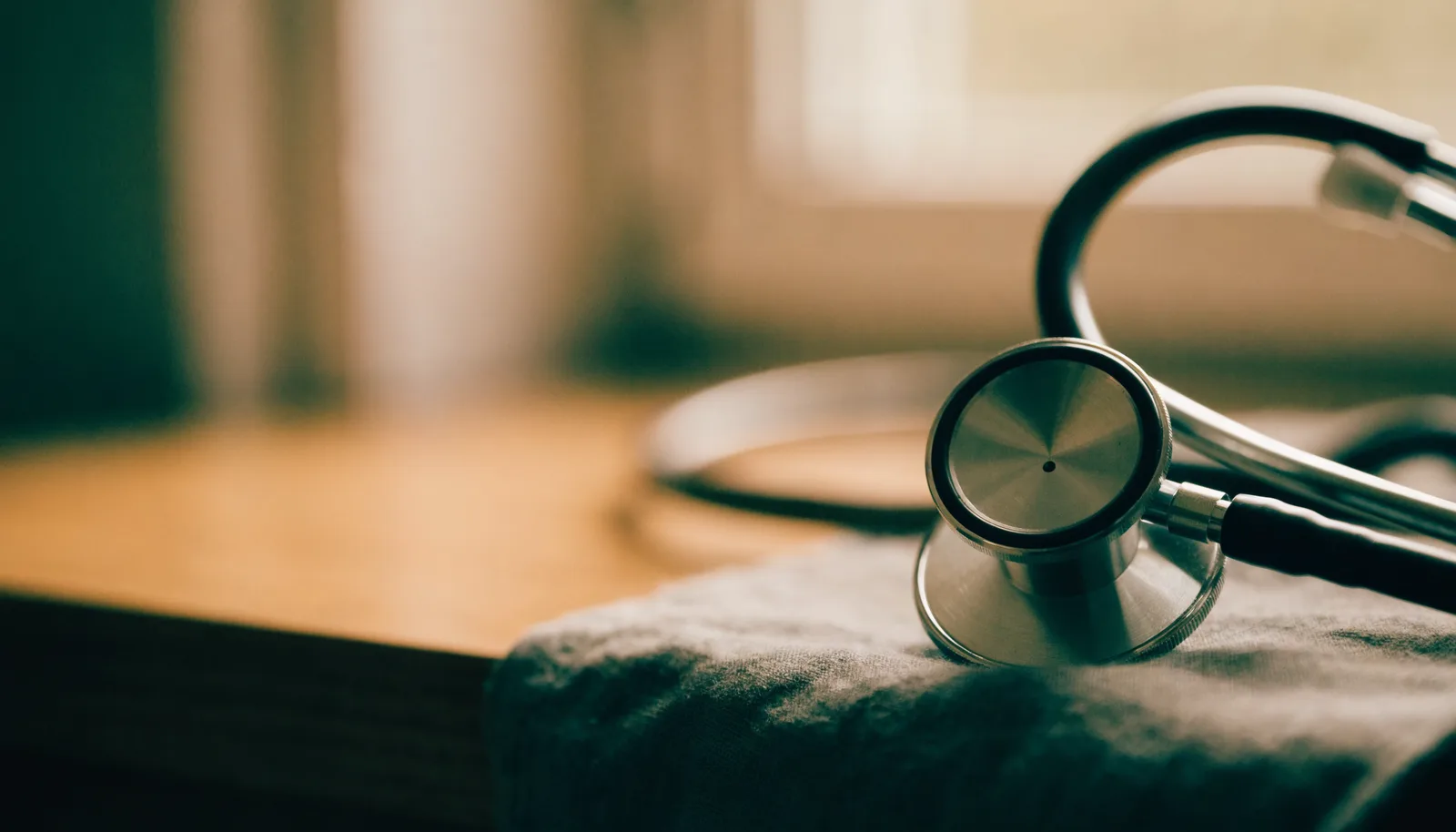 A stethoscope resting on folded cloth beside a window